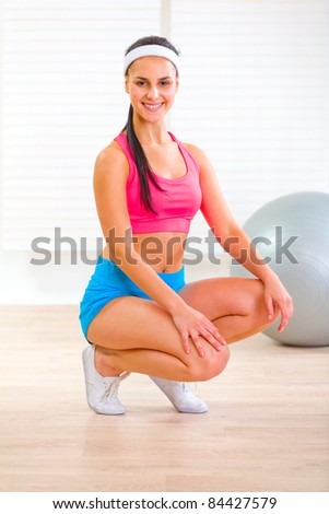 stock photo Smiling fit pretty girl squatting down