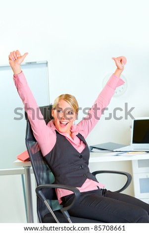 Happy modern business woman sitting at workplace rejoicing success