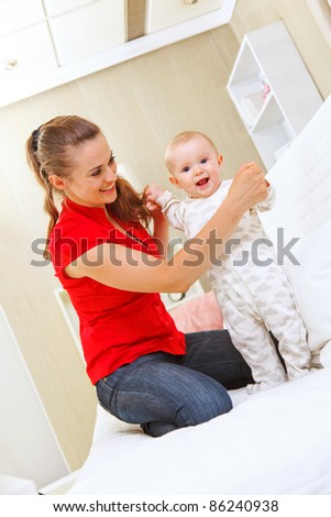 Happy mother helping baby learn to walk
