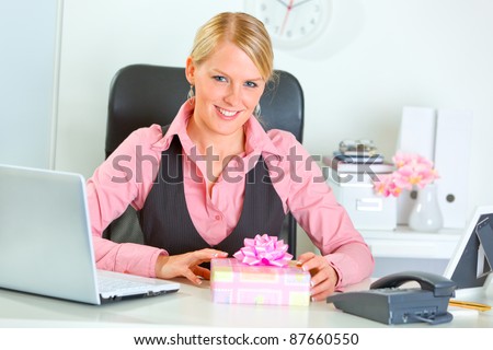Happy business woman with present box at office desk