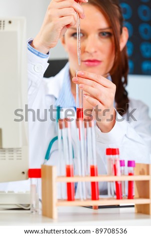 Female medical doctor working with test tube at cabinet