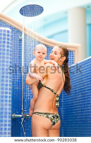 Young mom with baby taking shower - stock photo