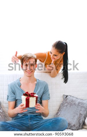 Girl uncover eyes to happy boyfriend with present in hand