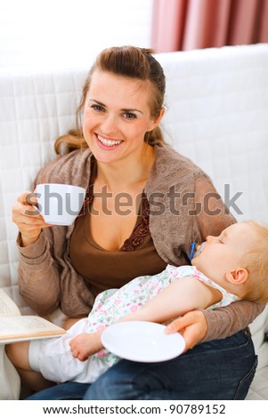 Happy mother resting while baby sleep by having tea and reading book