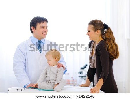 Pediatric doctor talking with mother while baby playing with stethoscope