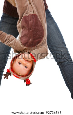Mother holding cute baby in costume of Santa Claus\'s reindeer upside down