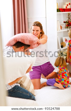 Happy family having a pillow fight in bed