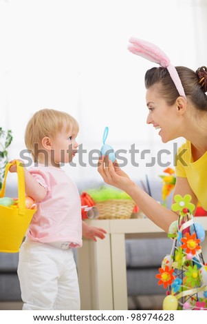 Mother helping baby collecting Easter eggs