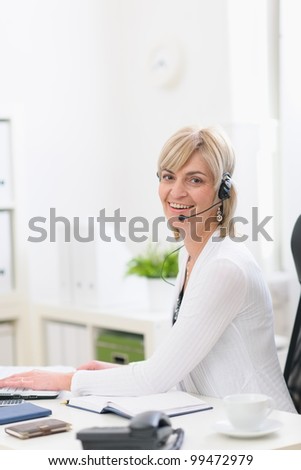 Happy middle age business woman with headset working at office