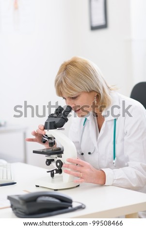 Middle age female researcher looking in microscope