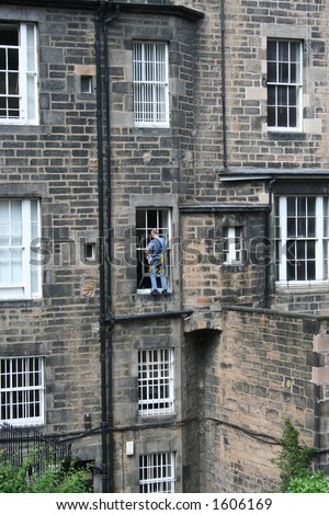 Window cleaner at work standing on window ledge