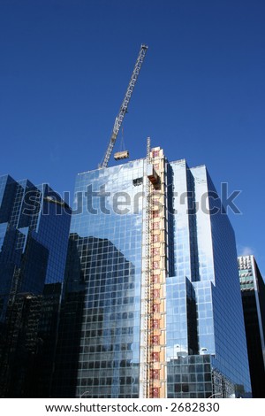 Skyscraper construction crane lifting load of scaffolding