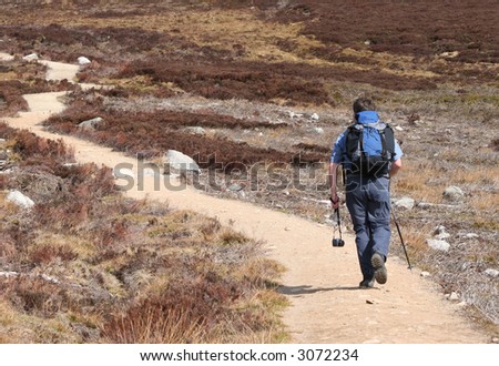man walking in countryside with rucksack and camera
