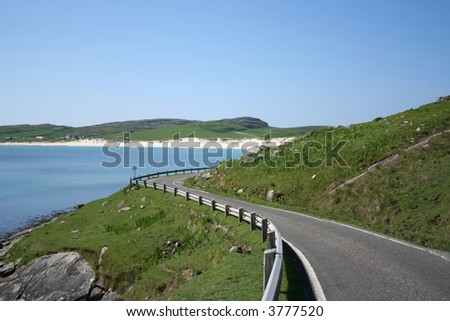 bend in coastal road with white sand