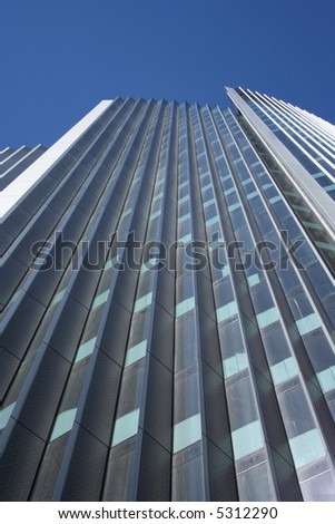 looking up at tall skyscraper with blue sky