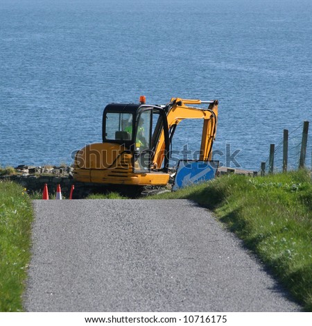 excavator digging hole beside country road