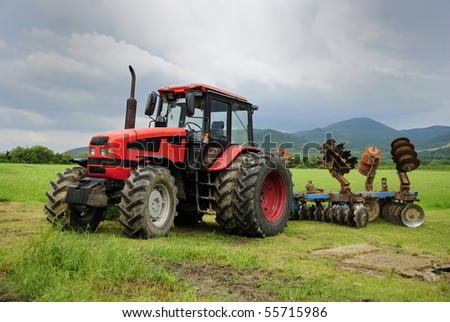 Red tractor parked on a grass field