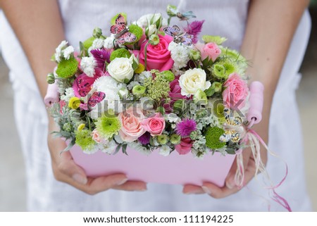 flowerpot with small pink, green and white flowers for wedding decoration at girl's hands