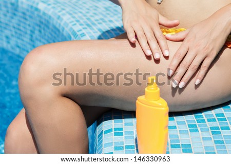 girl putting solar cream on body on summer day  outdoors near pool under sunshine