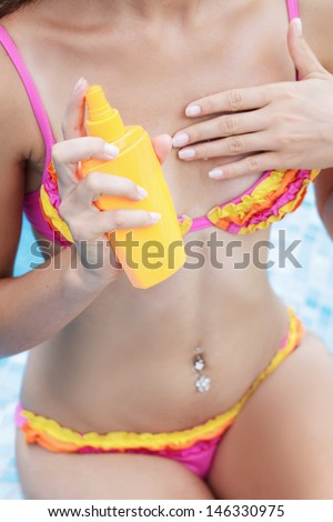girl putting solar cream on body on summer day outdoors