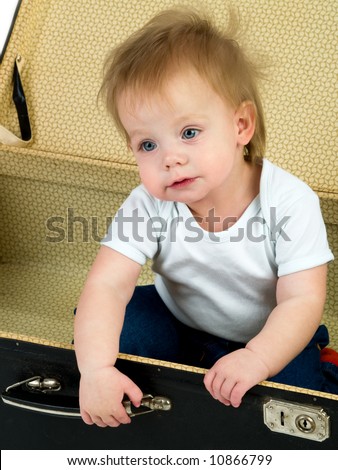 small child sitting in a suitcase isolated on white