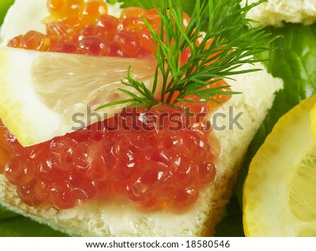 close up of a little snack with salmon caviar decorated with dill and lemon