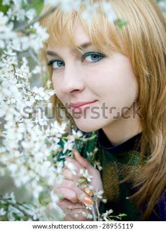portrait of a beautiful girl smelling white flowers in the garden