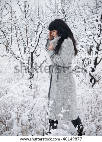 young woman in fur coat outdoors in snow garden