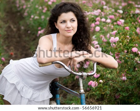 beautiful girl with bicycle in rose field