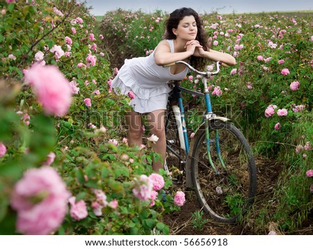 beautiful girl with bicycle in rose field