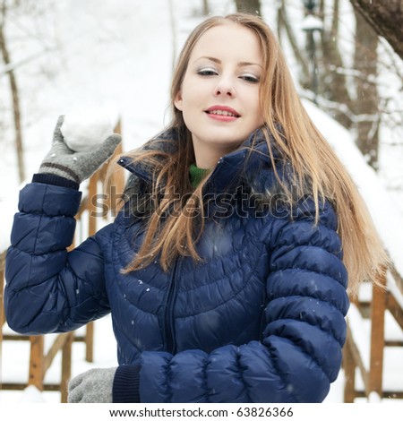 young woman in blue coat outdoors playing with snow in snow forest