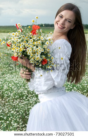 young happy girl with bouquet in daisy field