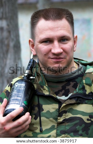 Strong man with paintball gun in the forest