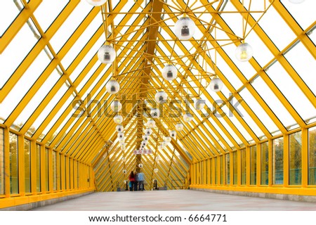 Yellow glass corridor in bridge and people walking