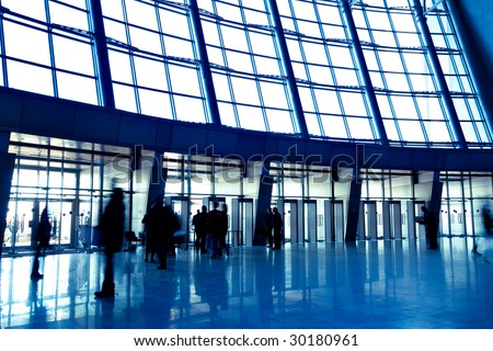 People in wide blue enter hall window in exposition center, left copmosition
