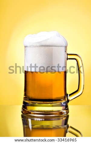 Full mug of lager beer on yellow