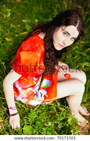 Top view to the girl in red dress seating in the grass