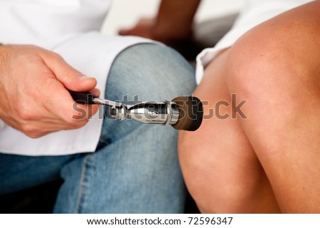 The neurologist testing knee reflex on a female patient using a hammer