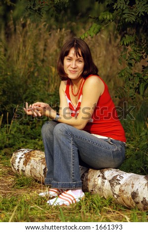 Brown-haired young woman sitting on the wooden log