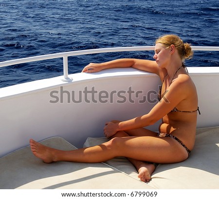 Tanned bikini girl resting on the yacht board
