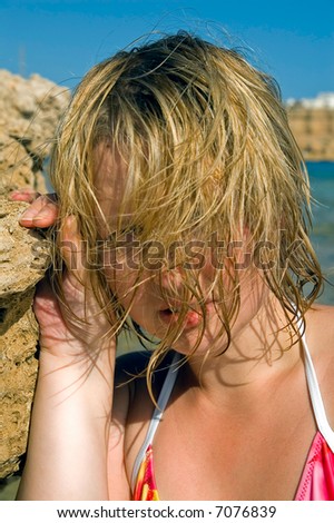 Portrait of young bikini woman with wet hair posing near cliff