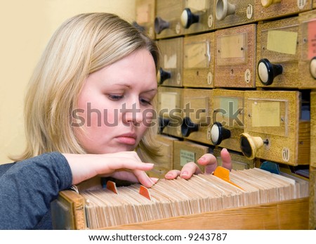 Young student woman works with library card index