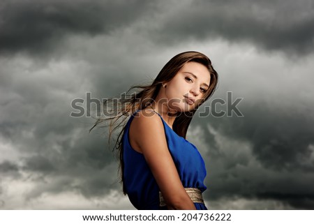 portrait of beautiful model on dark sky background. before storm