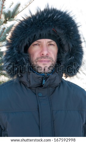 Portrait of confident man wearing fur hooded parka coat at the spruce