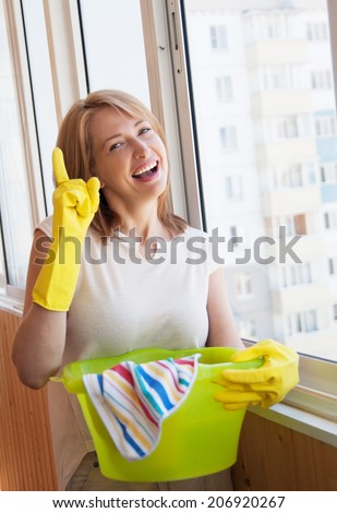 Happy woman washes window in the new apartment