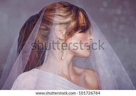 beautiful bride wearing off shoulder dress and with hair in ponytail wearing veil on the sparkling bokeh background.