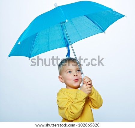 little boy wearing a bright yellow shirt holding a blue umbrella in his hand over a light studio background
