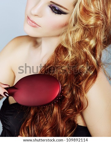 beautiful woman brushing long curly red hair over her shoulder - focus on the hair