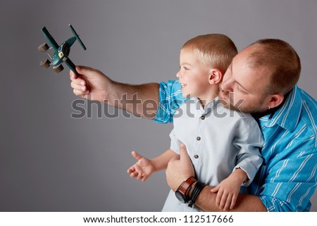father in thirties and toddler boy of three years old play with airplane toy on studio background