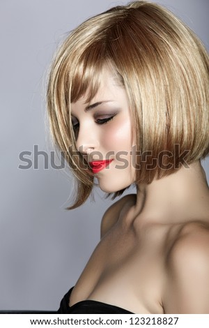 beautiful young woman with short blond hair in a bob wearing red lipstick on studio background